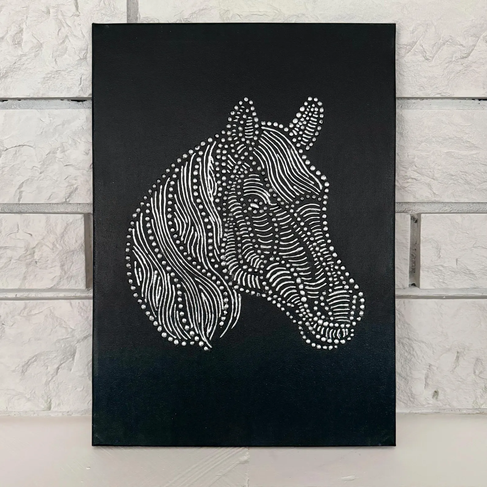 Black and silver horse wall art displayed on a white wall with a pink chair and gold floor lamp