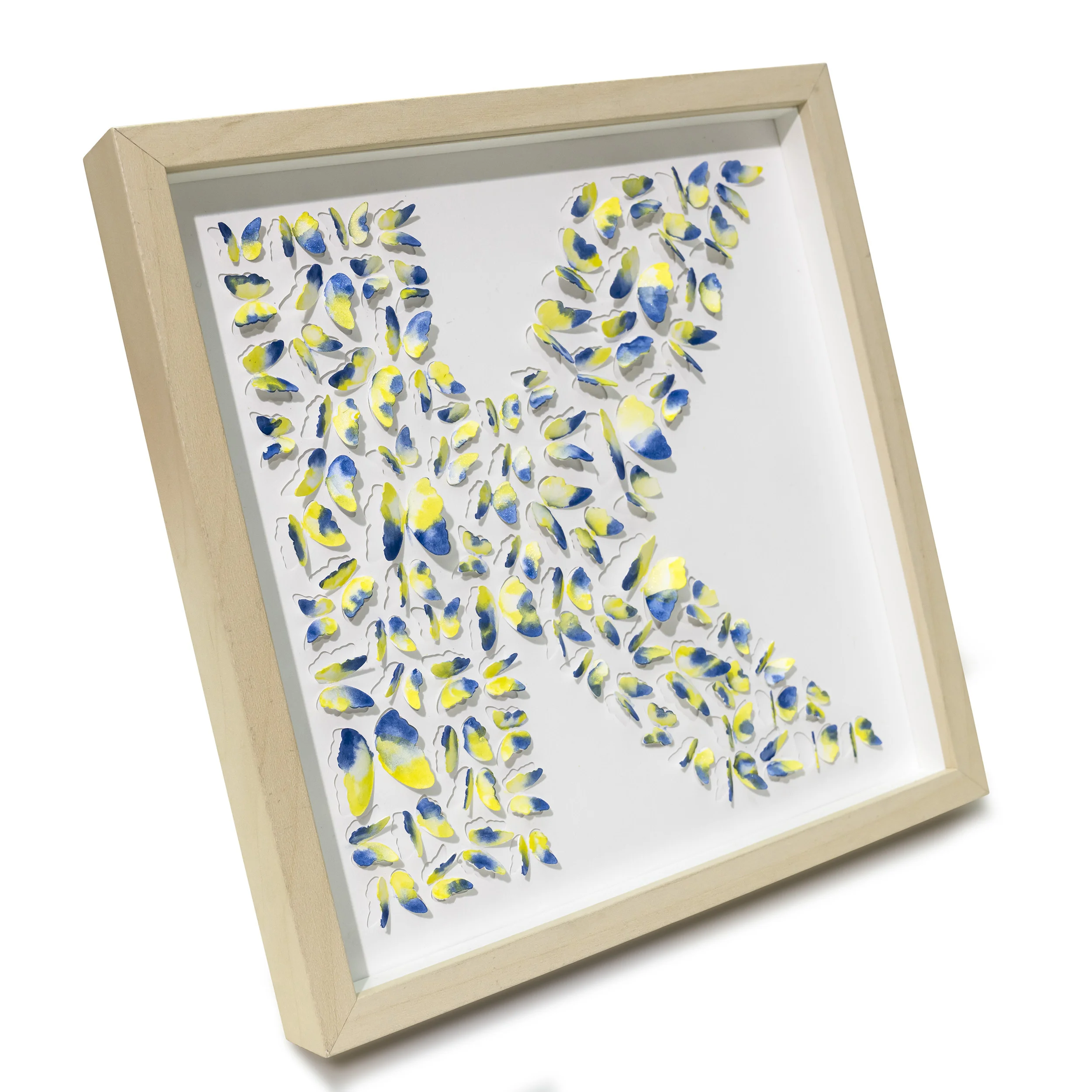 Angled view of blue and yellow butterfly letter K 3D watercolor wall art in a light wood shadow box frame