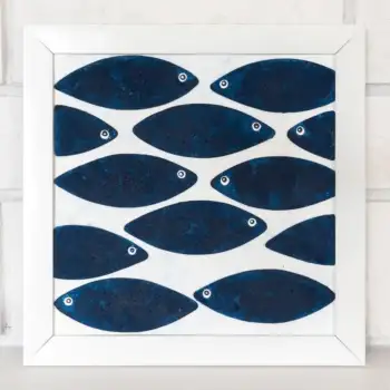 Indigo blue fish wall art displayed above a black chair with yellow cushions and green plants